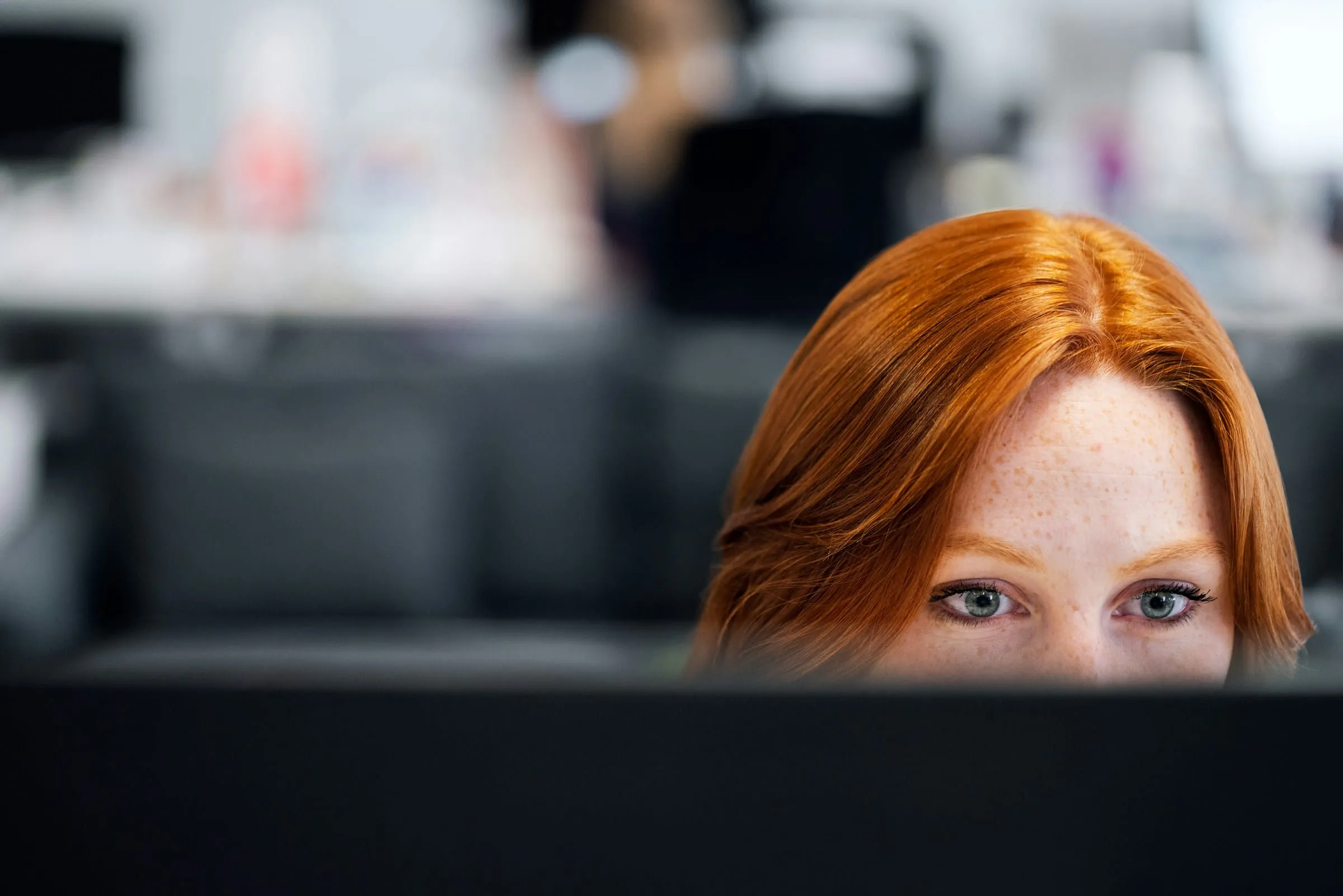 Vrouw kijkt over een computerscherm, symbool voor digitale toegankelijkheid