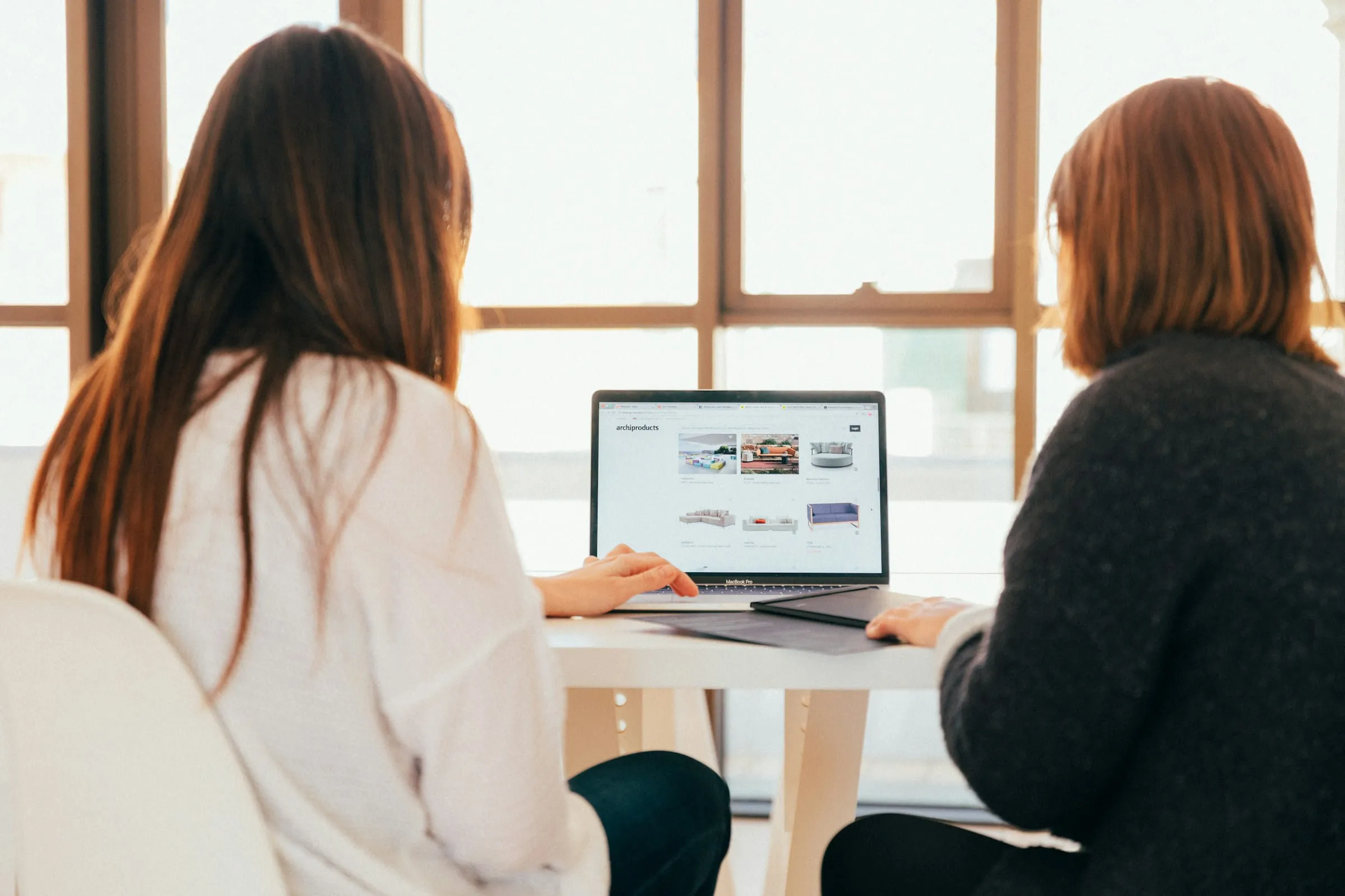 Twee vrouwen bekijken samen een website op een laptop
